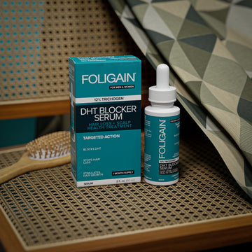 編み込みの椅子の座面に置かれたFOLIGAIN DHTブロッカーセラムのボトルと箱。