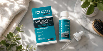 大理石の台の上でヘアブラシの横に置かれたFOLIGAIN DHTセラムの箱、ボトル、スポイト。