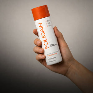 TRIOXIDIL 2%配合のFOLIGAIN男性用トリプルアクションコンディショナーを持つ手。