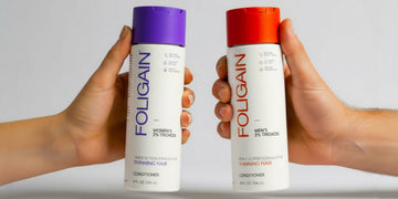 紫とオレンジのキャップが付いたFOLIGAIN女性用と男性用のTRIOXIDILコンディショナーを持つ両手。