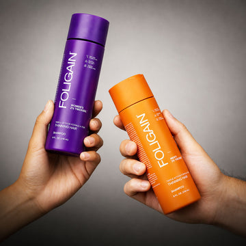 FOLIGAIN女性用と男性用のTRIOXIDILシャンプーのボトルを持つ両手。
