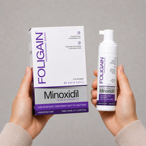 FOLIGAIN女性用ミノキシジル5%外用フォームの箱とボトルを持つ両手。