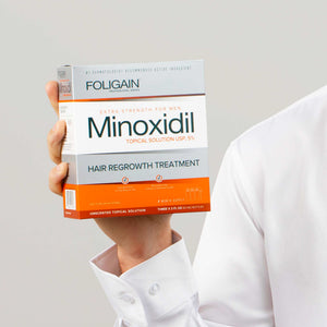 FOLIGAIN男性用ミノキシジル5%外用液の箱を持つ手。