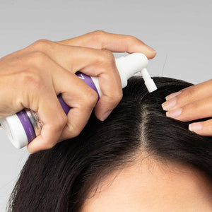 髪の分け目に沿ってFOLIGAIN TRIOXIDIL外用トリートメントを塗る女性